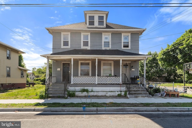 american foursquare style home with a porch and a shingled roof