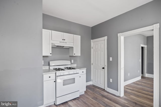 kitchen with white gas stove, under cabinet range hood, wood finished floors, white cabinetry, and light countertops