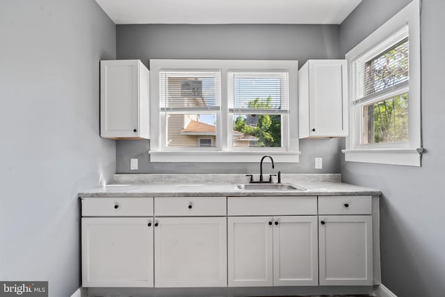 kitchen with a sink, white cabinetry, and light countertops