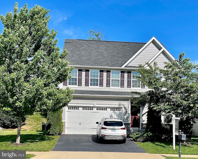 traditional-style house with asphalt driveway, an attached garage, and a front yard