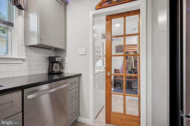 kitchen featuring dishwasher, gray cabinets, dark countertops, backsplash, and baseboards