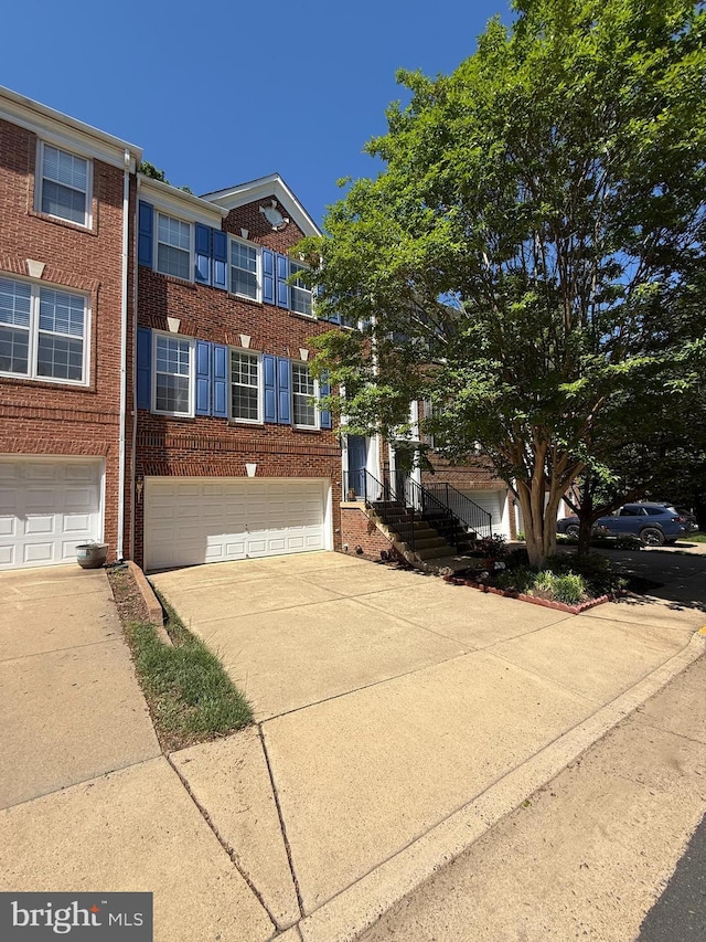 view of front facade with brick siding, an attached garage, and driveway