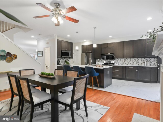 dining space with a ceiling fan, recessed lighting, light wood-style floors, and stairway