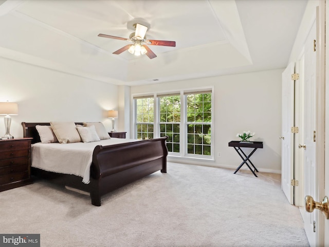 carpeted bedroom featuring a tray ceiling, a ceiling fan, and baseboards