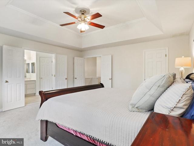 bedroom featuring light carpet, crown molding, connected bathroom, a raised ceiling, and ceiling fan