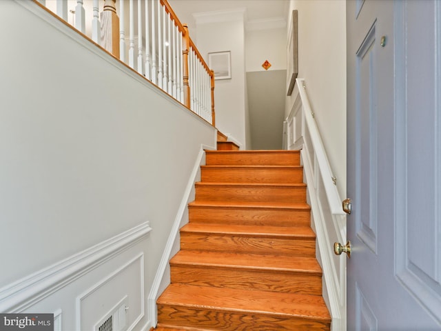 staircase with ornamental molding and a towering ceiling