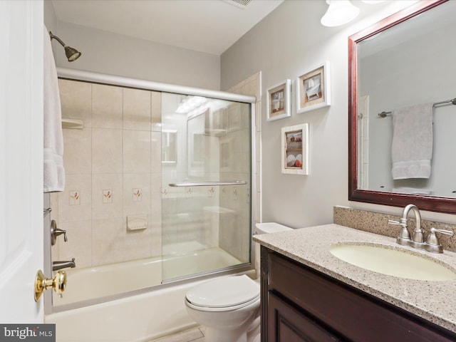 bathroom featuring toilet, vanity, and combined bath / shower with glass door