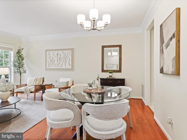 dining room featuring a chandelier, ornamental molding, light wood-style flooring, and baseboards