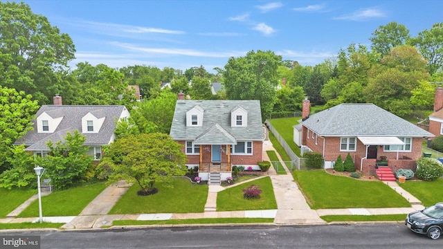 cape cod home with brick siding, a front yard, a chimney, and driveway