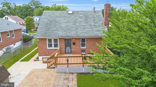 back of house featuring a patio, a deck, a chimney, and brick siding