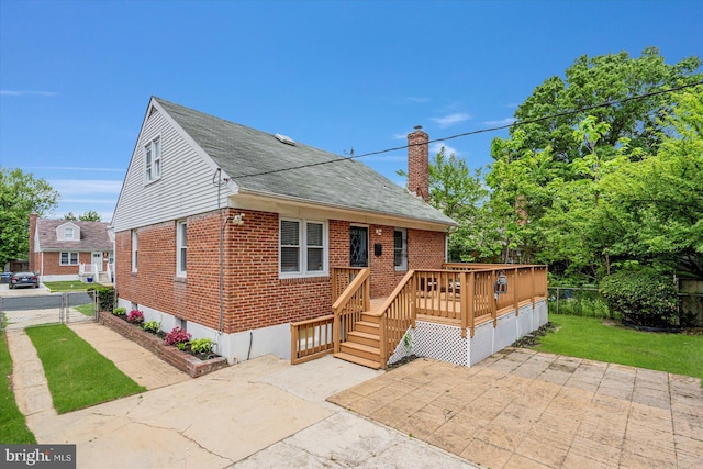 view of front of house featuring brick siding, a patio, a wooden deck, a chimney, and roof with shingles