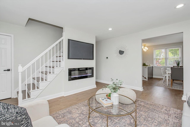 living room featuring stairs, wood finished floors, recessed lighting, a glass covered fireplace, and baseboards