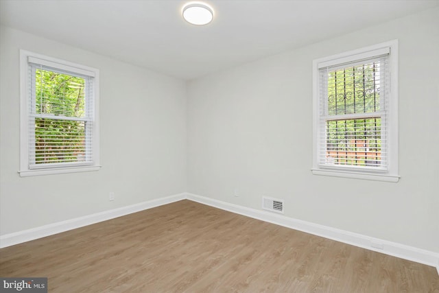 spare room featuring healthy amount of natural light, baseboards, and wood finished floors