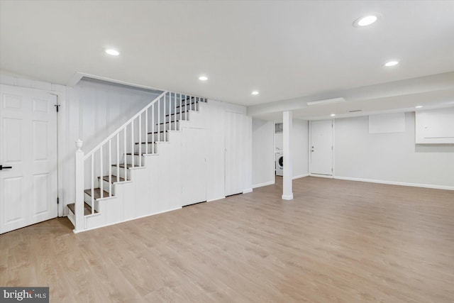 finished below grade area featuring washer / dryer, stairs, light wood finished floors, baseboards, and recessed lighting