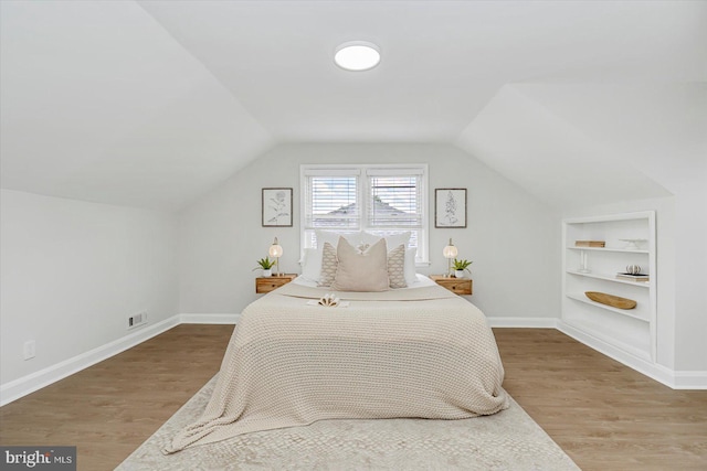 bedroom with lofted ceiling, wood finished floors, and baseboards