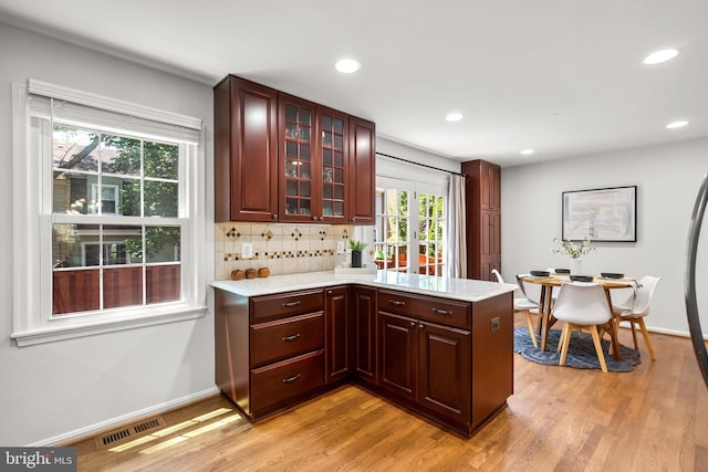 3901 Bradwater St, Fairfax, VA 22031 - kitchen featuring a peninsula, light wood-style floors, glass insert cabinets, recessed lighting, and tasteful backsplash