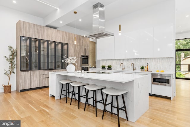 3554 Military Rd, Arlington, VA 22207 - kitchen featuring modern cabinets, island exhaust hood, light wood-style floors, a breakfast bar area, and recessed lighting