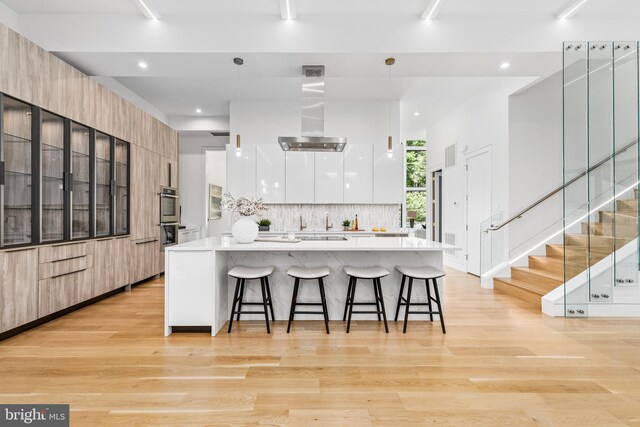 3554 Military Rd, Arlington, VA 22207 - kitchen featuring modern cabinets, a kitchen breakfast bar, backsplash, light wood-type flooring, and recessed lighting