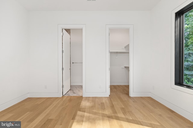 3554 Military Rd, Arlington, VA 22207 - unfurnished bedroom featuring light wood-style flooring, a spacious closet, baseboards, and a closet