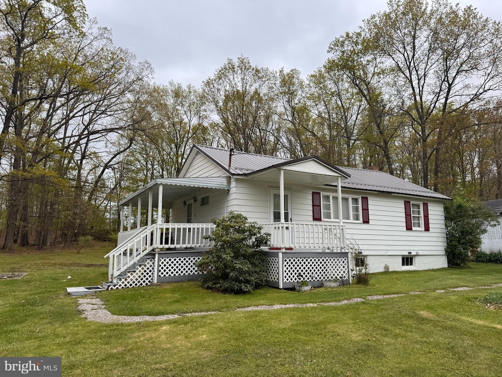 view of front of house featuring a porch, a front lawn, and metal roof