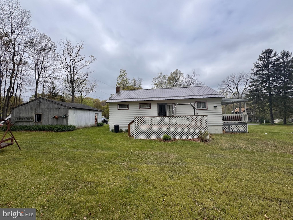 back of house featuring a lawn, metal roof, and a chimney