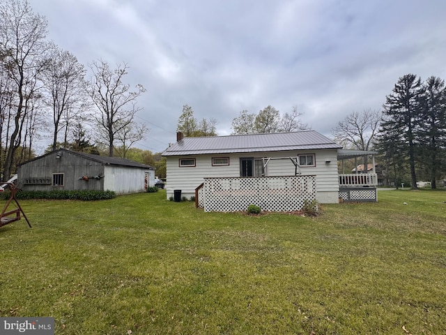 back of house featuring a lawn, metal roof, and a chimney