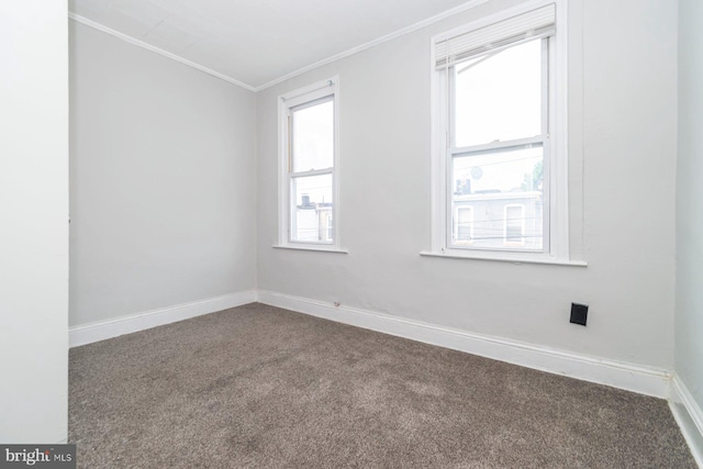 empty room with crown molding, dark colored carpet, and baseboards