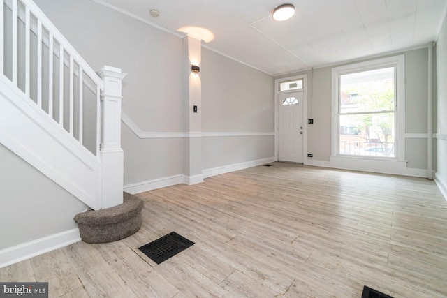 entryway featuring stairway, light wood-style floors, baseboards, and ornamental molding