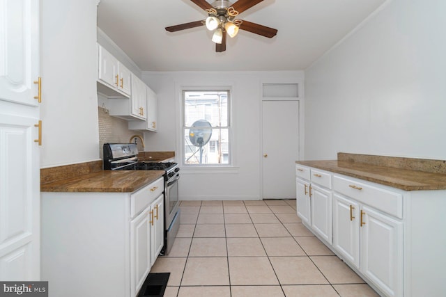 kitchen featuring stainless steel gas range, ceiling fan, white cabinetry, light tile patterned floors, and dark countertops