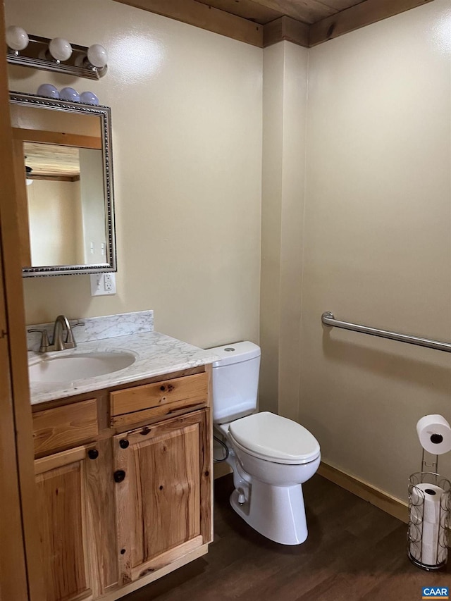 half bath featuring wood finished floors, toilet, and vanity