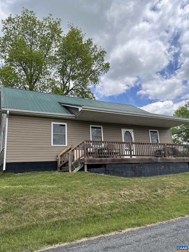 manufactured / mobile home featuring a deck, a front lawn, and metal roof