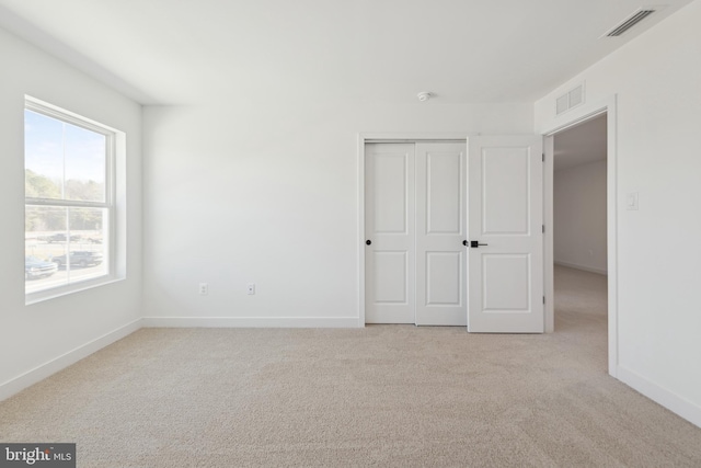 unfurnished bedroom featuring light carpet, baseboards, and a closet