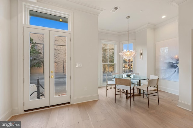 dining area featuring french doors, light wood-style floors, baseboards, a chandelier, and ornamental molding
