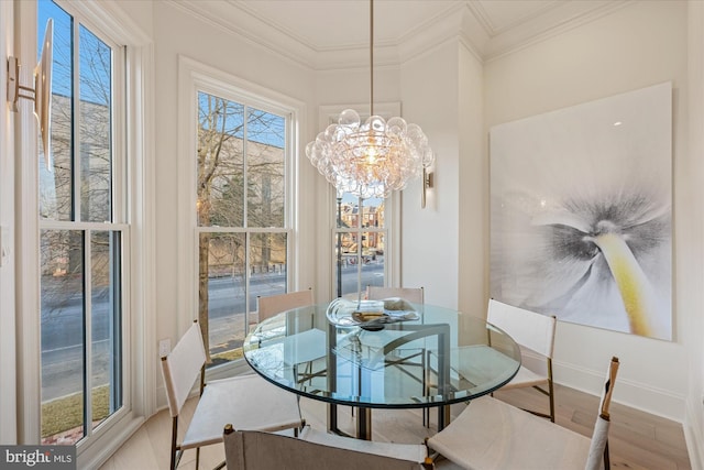 dining space with a chandelier, wood finished floors, ornamental molding, and baseboards