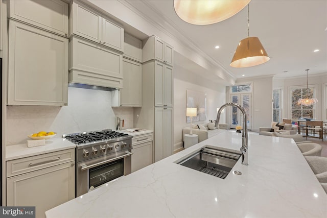 kitchen featuring stainless steel range, open floor plan, a sink, crown molding, and tasteful backsplash