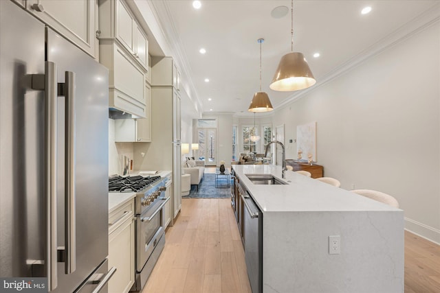 kitchen with high quality appliances, a sink, crown molding, a kitchen island with sink, and open floor plan