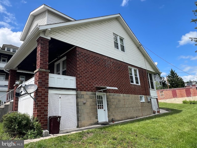 view of side of home with brick siding and a yard