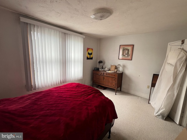 bedroom featuring light carpet, baseboards, and a textured ceiling