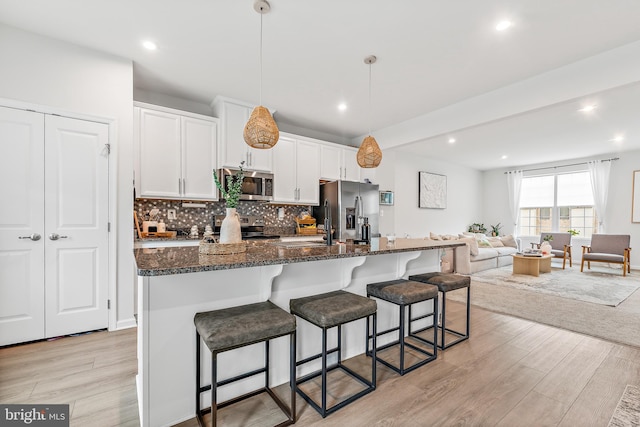 2314 Emerson Ln, Fredericksburg, VA 22401 - kitchen with stainless steel appliances, light wood-style flooring, a kitchen breakfast bar, white cabinetry, and an island with sink
