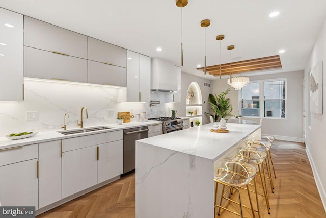728 S Warnock St, Philadelphia, PA 19147 - kitchen featuring a sink, a breakfast bar area, appliances with stainless steel finishes, wall chimney exhaust hood, and white cabinets