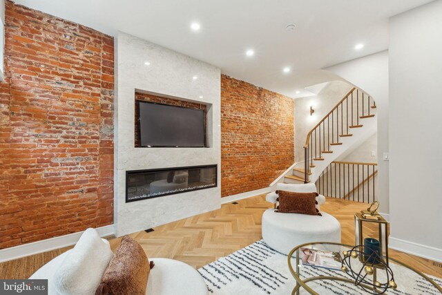 728 S Warnock St, Philadelphia, PA 19147 - living room with baseboards, stairs, a glass covered fireplace, brick wall, and arched walkways
