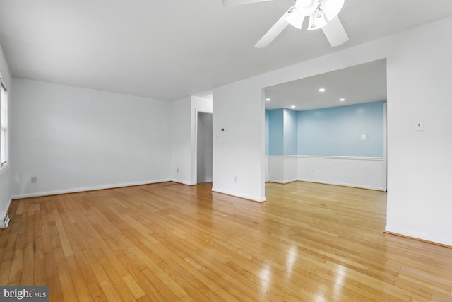 empty room featuring light wood finished floors, a ceiling fan, and baseboards