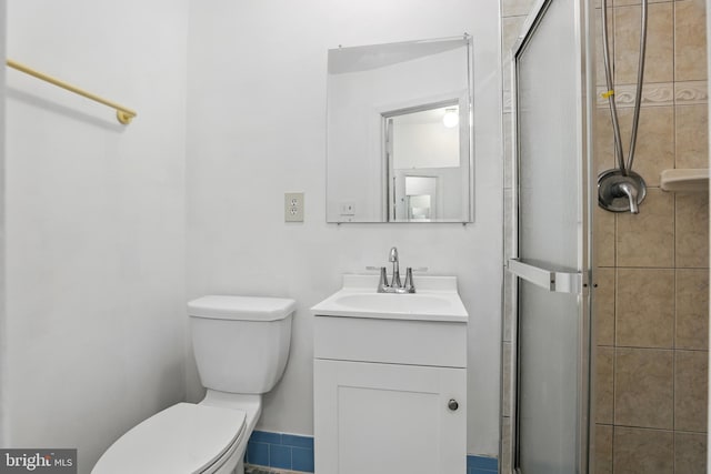 bathroom featuring a shower stall, toilet, and vanity
