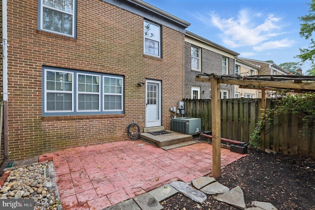 rear view of house with central AC, a patio area, brick siding, and fence