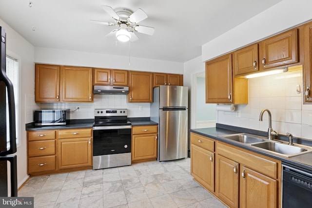 kitchen with black appliances, under cabinet range hood, a sink, ceiling fan, and dark countertops