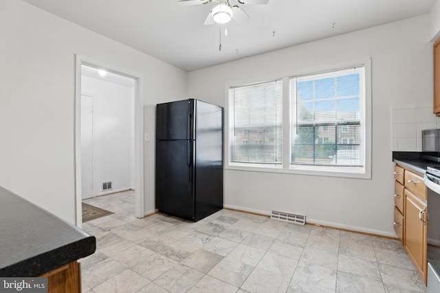 kitchen with freestanding refrigerator, dark countertops, ceiling fan, baseboards, and brown cabinets