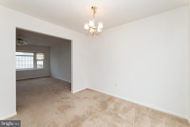 carpeted empty room featuring a chandelier, baseboards, and a ceiling fan