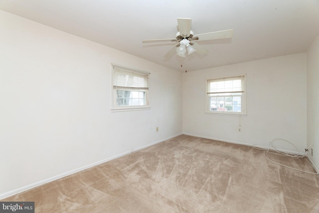 carpeted empty room featuring healthy amount of natural light, baseboards, and a ceiling fan