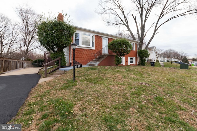 view of front of home featuring brick siding, a chimney, and driveway