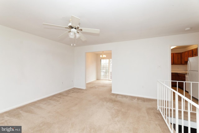 spare room with ceiling fan, light colored carpet, a chandelier, baseboards, and a smoke detector